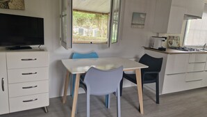 Moderni keittiö, jossa on ruokailutila, TV-taso ja ikkuna, josta avautuu näkymä vehreään maisemaan.