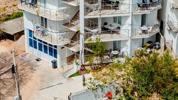 A multi-story building with balconies, solar panels, and outdoor seating.