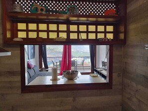 A room with a large window, a wooden lattice, and a view of a balcony with chairs and a table. - Apartment with a beautiful view and a balcony (San Marcos)