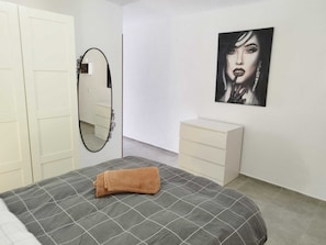 Ein Schlafzimmer mit Bett, Schminktisch, Spiegel und einem Wandbild.