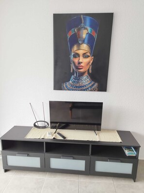 A flat-screen TV on a black entertainment unit with three drawers and a remote control on a beige cloth. - Apartment with a beautiful view and a balcony (San Marcos)