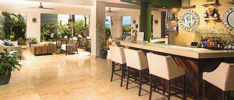 A spacious bar area with a long counter, multiple bar stools, and a variety of bottles and glasses.