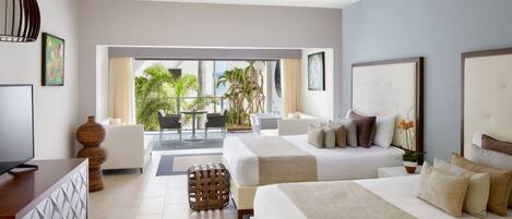 A hotel room with two beds, a TV, a ceiling fan, and a balcony with a view of palm trees.