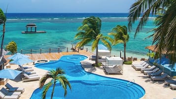 A resort pool area with lounge chairs, umbrellas, and a view of the ocean.