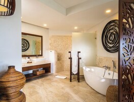 Un baño moderno con una bañera independiente, un espejo grande y un adorno de pared decorativo.