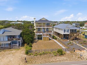 A two-story house with a balcony, a covered porch, and a wooden deck. - Steps from Beach with Ocean Views and Fresh Updates (Oak Island)