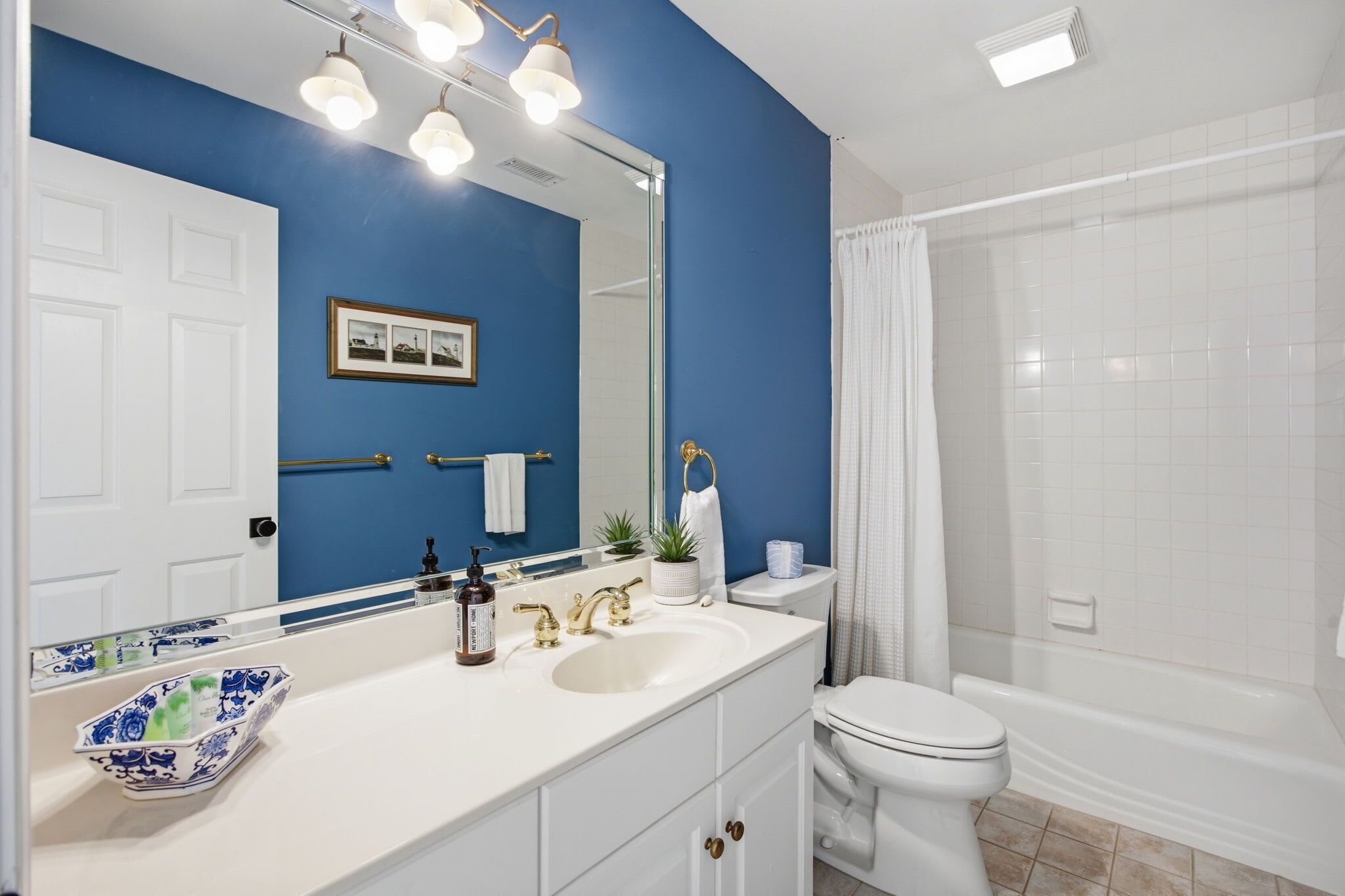 A bathroom with a white sink, a toilet, a bathtub, a shower, and a large mirror with lights.