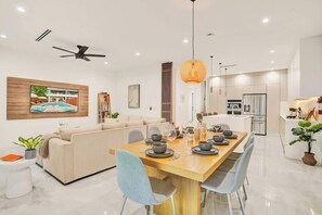 A modern kitchen with a dining area, a ceiling fan, and a large window. - Las Olas-8 BD with Two HTD Pool-Jacuzzi-BBQ-Games (Fort Lauderdale)