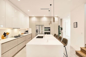 A modern kitchen with a central island, stainless steel appliances, and pendant lighting. - Las Olas-8 BD with Two HTD Pool-Jacuzzi-BBQ-Games (Fort Lauderdale)