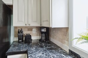 A kitchen with white cabinets, a marble countertop, a coffee maker, and a toaster. - Sunny Side Up & Down Duplex Center St Folly Beach (folly beach)