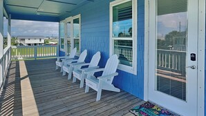 Un portico coperto con poltrone Adirondack bianche, facciata blu e vista sulla campagna circostante.