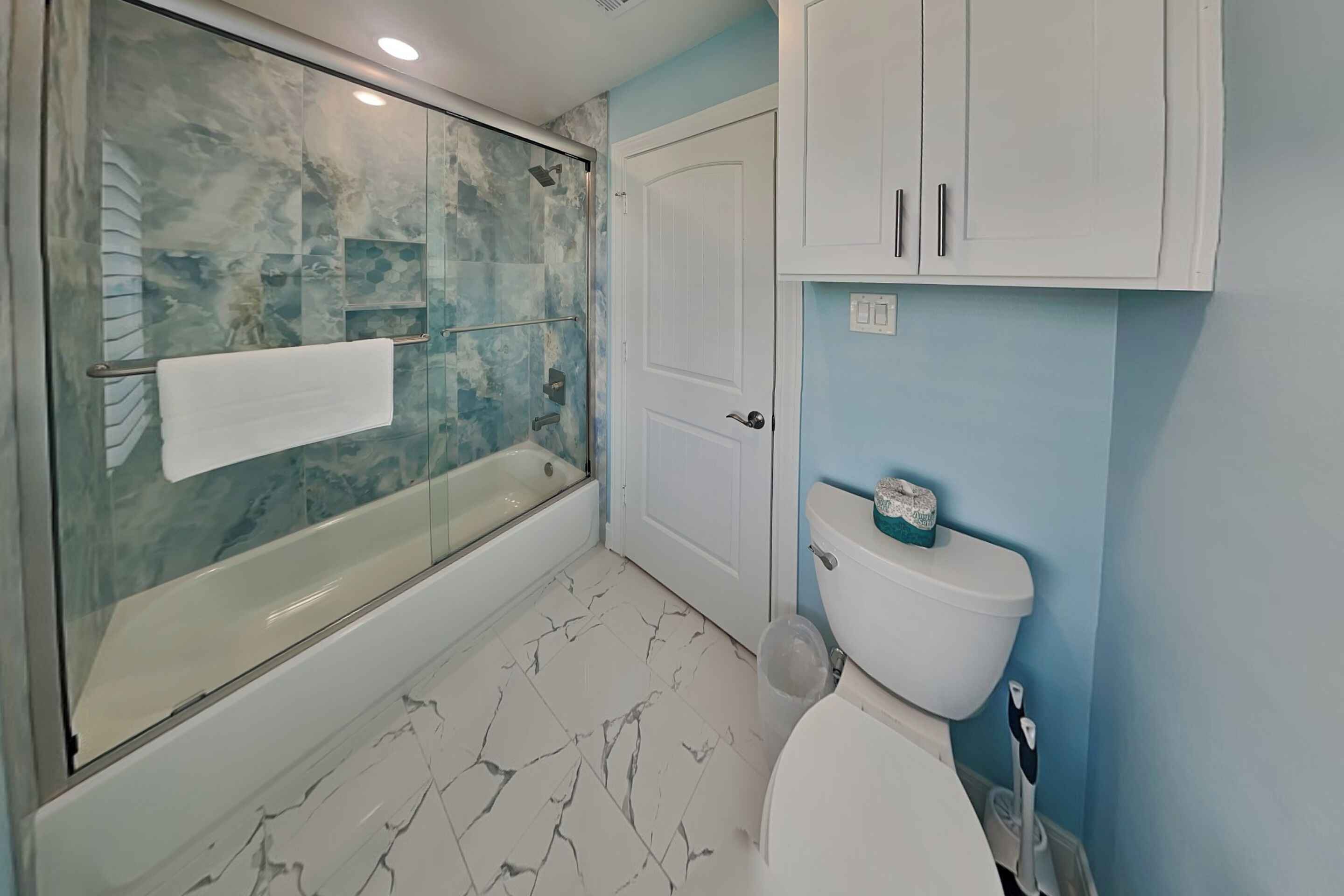 A bathroom with a glass-enclosed shower, a toilet, and a cabinet.