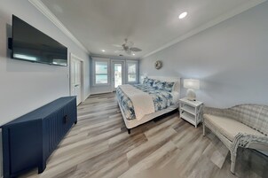 A bedroom with a bed, bedside table, lamp, and a TV mounted on the wall.