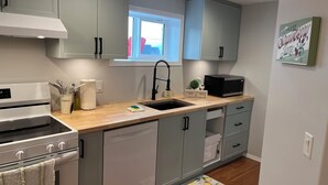 A modern kitchen with grey cabinets, a black microwave, and a sink. -        Salmon Arm Comfortable 2 Bedroom in town, 5 minute drive to the beach! (Salmon Arm)