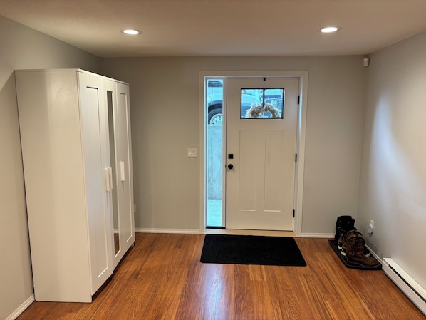 A hallway with a white door, a black mat, and a pair of boots.