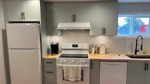 A kitchen with a refrigerator, stove, oven, and a window with a view of the outside. -        Salmon Arm Comfortable 2 Bedroom in town, 5 minute drive to the beach! (Salmon Arm)
