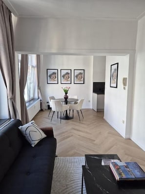 Una sala de estar moderna con un sofá, una mesa de centro y un comedor con sillas y una mesa.