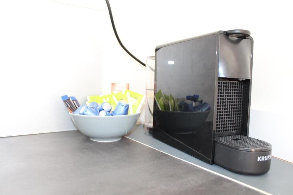 Una cafetera con un panel de control y un recipiente con cápsulas de café.