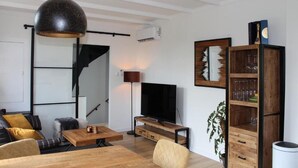 A modern living room with a wooden coffee table, a television, a bookshelf, and a hanging light fixture. - Studio & Apartments Roermond (Roermond)