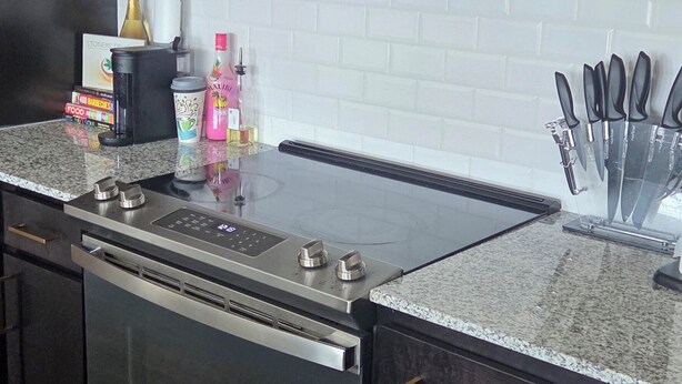 Uma cozinha com armários escuros, micro-ondas de aço inoxidável, forno embutido e bancada de granito.