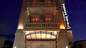 Un hotel con una entrada imponente, varios balcones y un cartel llamativo.