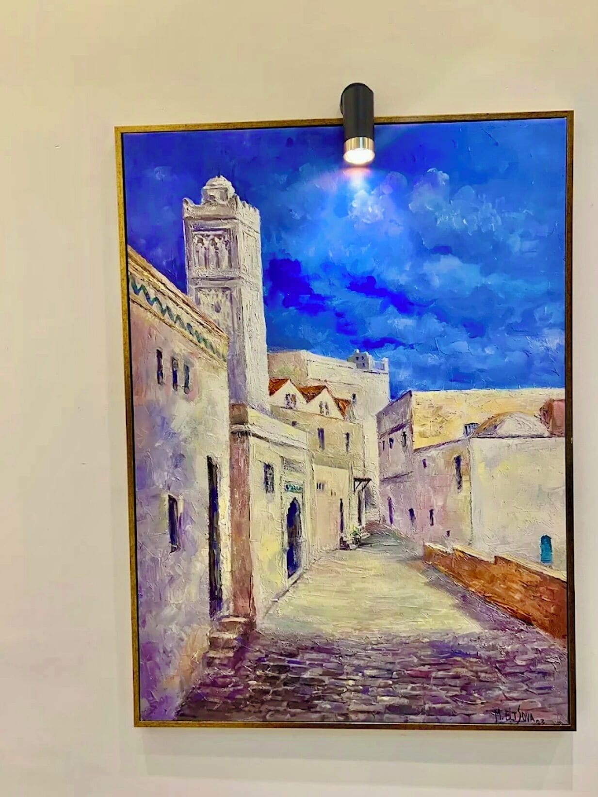 A painting of a narrow street with buildings on either side and a tower in the distance.