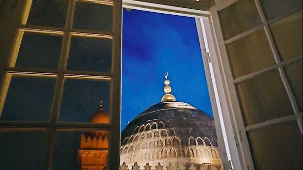 Una ventana con vista a la cúpula y al minarete de un edificio.