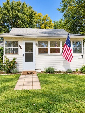 A single-story house with a front porch, a mailbox, and an American flag.