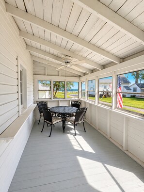 A covered patio with a table and chairs, large windows, and an American flag.