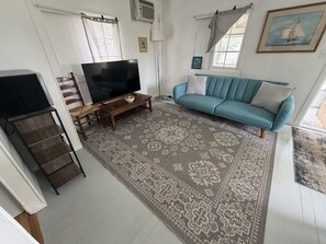 A living room with a sofa, TV, and a patterned rug. - Plum Point Cottage #17 (Huntingtown)