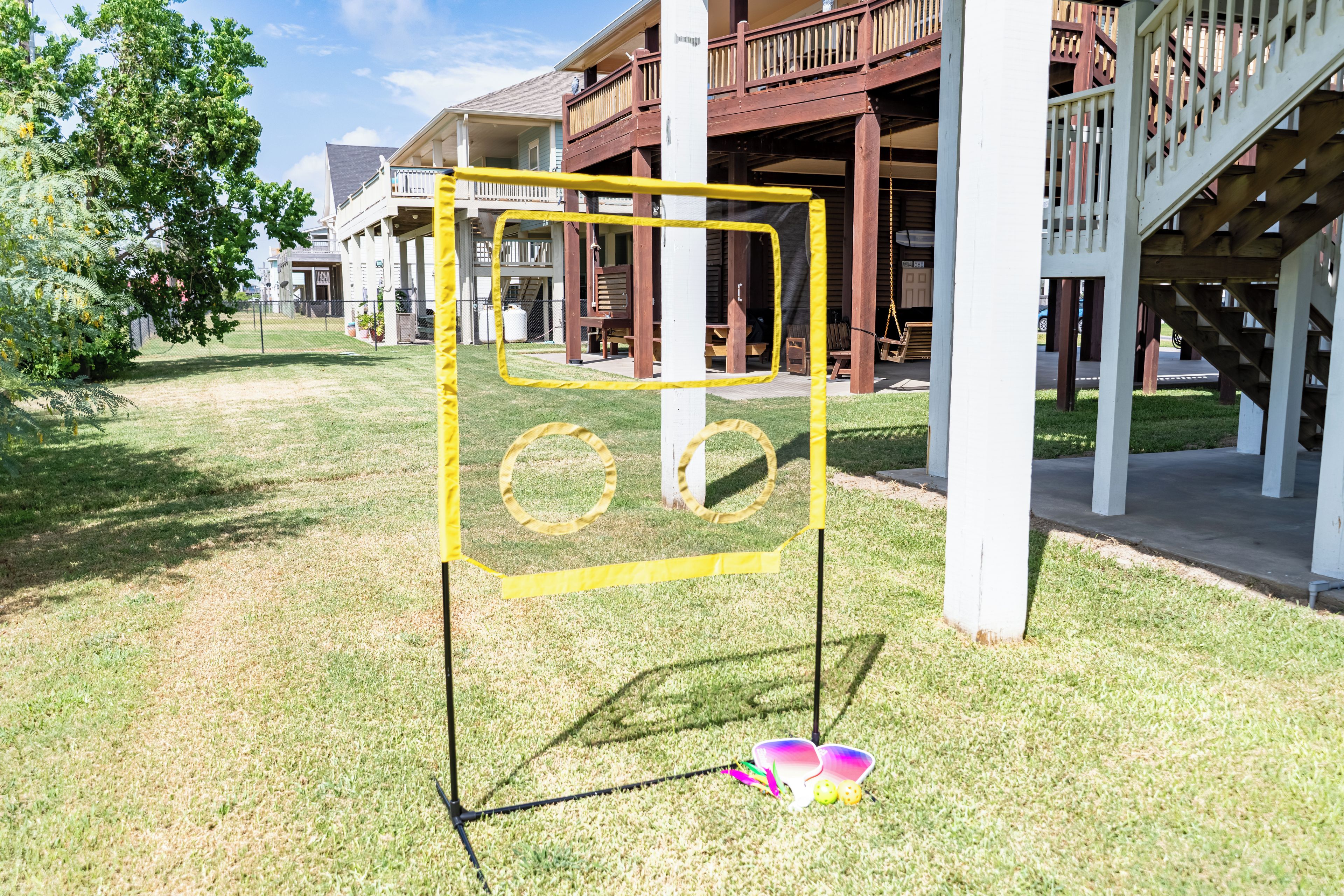 Une structure de jeux pour enfants avec une armature jaune et des balançoires, installée dans un espace herbeux avec un bâtiment en arrière-plan.