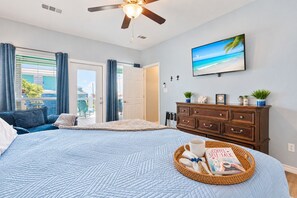 A bedroom with a bed, a dresser, a television, and a window with curtains. - Hot Tub, Fire pit, Day Bed, Two Main Suites, Beach (Bolivar Peninsula)