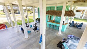 A covered outdoor seating area with a bar and chairs. - Crystal Beach Oasis, Hot Tub, 2 Decks, 2 Main Suites, Walk to the Beach, Dogs (Bolivar Peninsula)