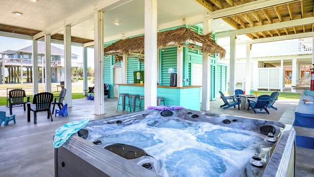 A hot tub area with a covered patio, chairs, and a bar area. - Crystal Beach Oasis, Hot Tub, 2 Decks, 2 Main Suites, Walk to the Beach, Dogs (Bolivar Peninsula)