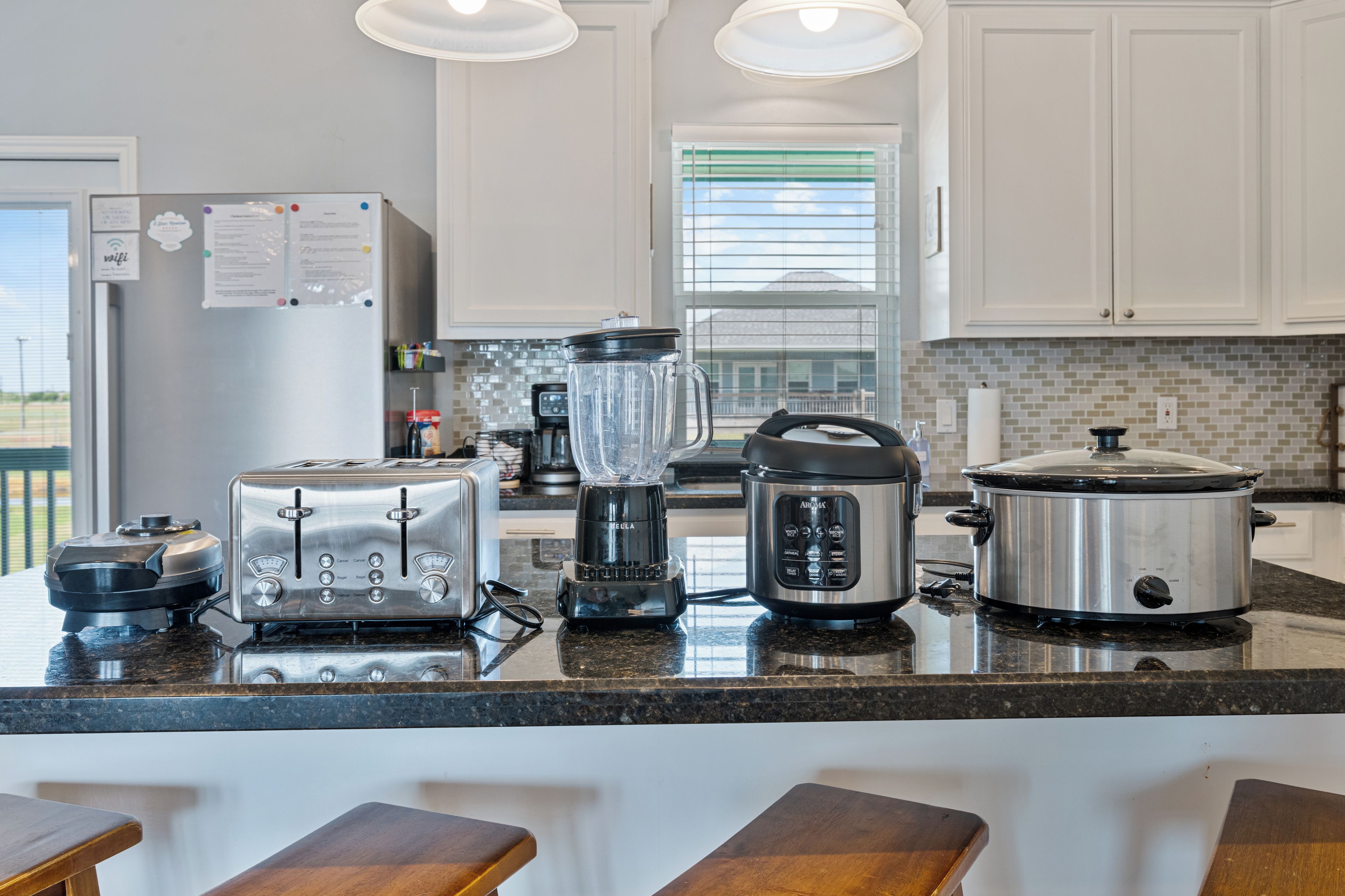 Een moderne keuken met een centraal eiland, voorzien van een broodrooster, blender, slow cooker en koffiezetapparaat.