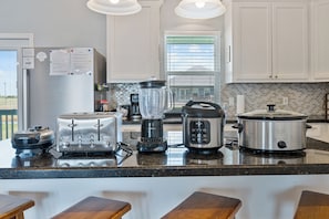 A modern kitchen with a central island, equipped with a toaster, blender, slow cooker, and a coffee maker. - Hot Tub, Fire pit, Day Bed, Two Main Suites, Beach (Bolivar Peninsula)