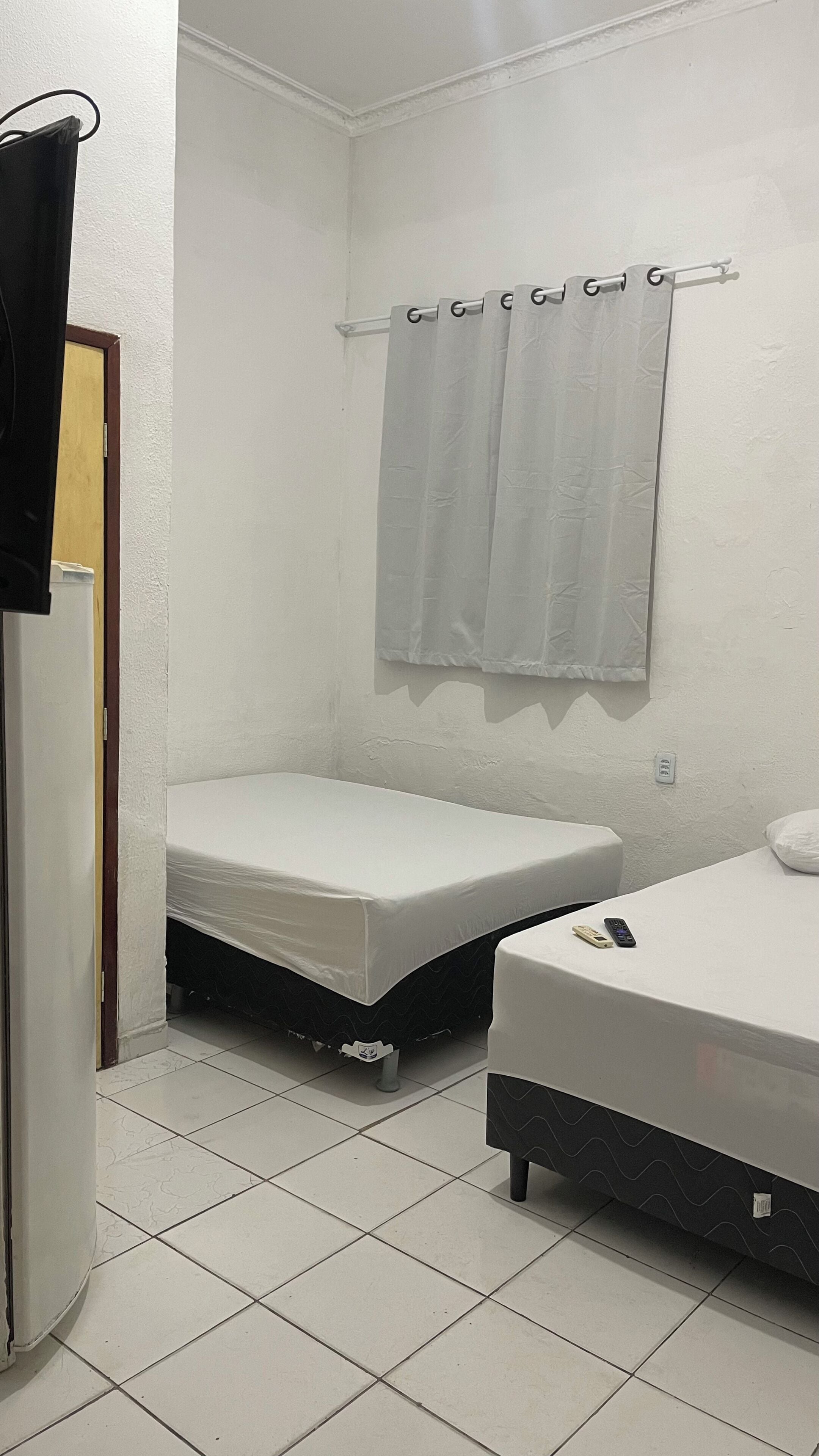 Quarto pequeno e compacto com duas camas, sanitário e chuveiro.