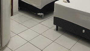 Quarto pequeno e compacto com duas camas, sanitário e chuveiro.