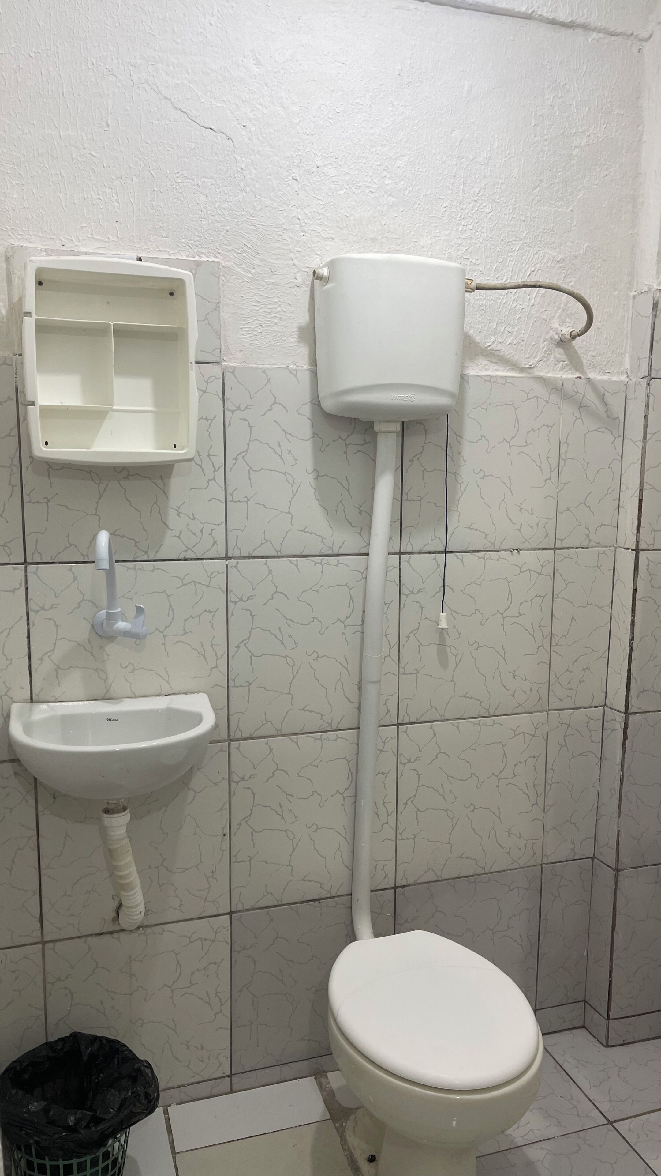 Un baño con inodoro, lavamanos y tanque de agua.