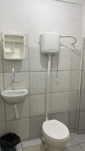 Un baño con inodoro, lavamanos y tanque de agua.