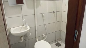 Um banheiro pequeno com vaso sanitário, pia e chuveiro.
