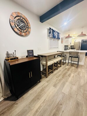 A dining area with a wooden table, chairs, a black cabinet, and a wall clock.
