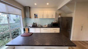 Uma cozinha moderna com uma janela grande, eletrodomésticos de aço inoxidável e bancada de mármore.