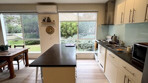 Cozinha moderna com ilha central, janelas amplas e vista para o verde.
