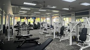 Een sportschool met plafondventilatoren, trainingsapparatuur en grote ramen.