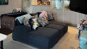 Een woonkamer met een bank, een televisie en een eethoek met een tafel en stoelen.