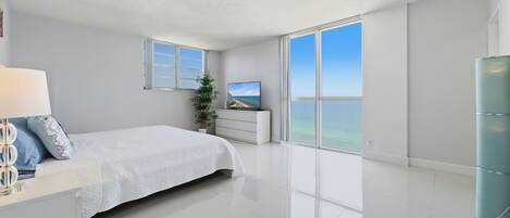 Un dormitorio moderno con una cama grande, un televisor y vistas al océano.