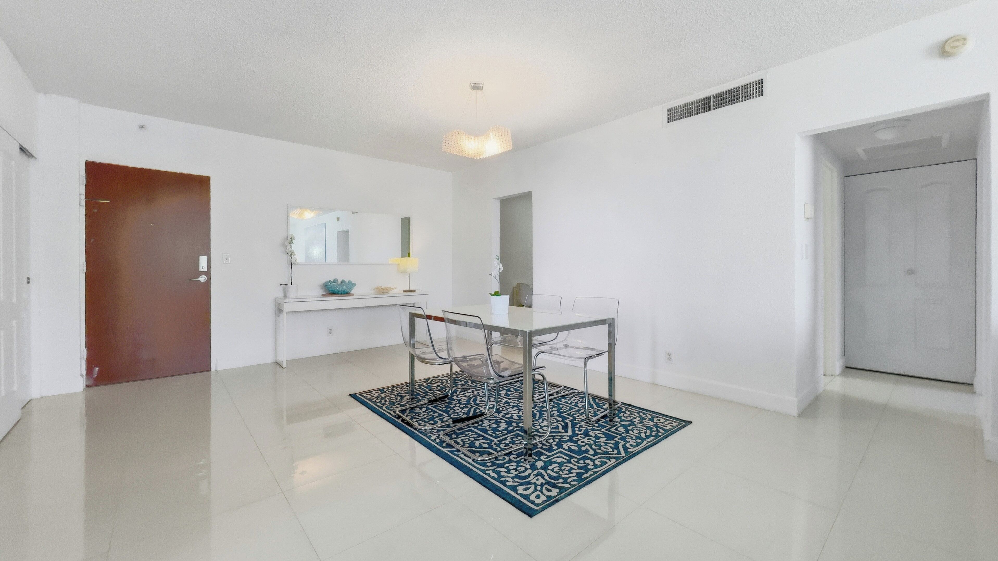 Une pièce moderne et bien éclairée, comprenant une table à manger, des chaises et un tapis décoratif.