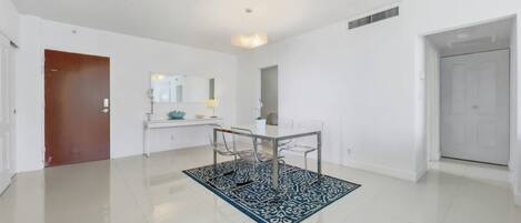 Une pièce moderne et bien éclairée, comprenant une table à manger, des chaises et un tapis décoratif.