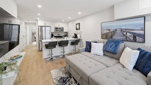 Um apartamento moderno com cozinha compacta, espaço de jantar, sala de estar com sofá e uma janela grande com vista.